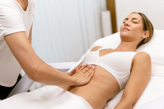 Middle-aged woman having a belly massage in a beauty salon. Body care treatment in a beauty centre.