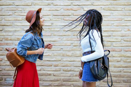 Two friends having fun together on the street. Multiethnic women.