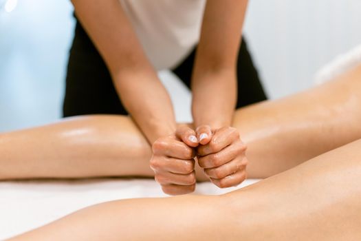 Woman receiving a leg massage with massage candle oil. Body care treatment in a beauty centre.