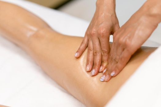 Woman receiving a leg massage with massage candle oil. Body care treatment in a beauty centre.