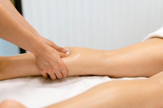 Middle-aged woman having a leg massage in a beauty salon. Body care treatment in a beauty centre.