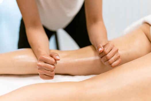 Woman receiving a leg massage with massage candle oil. Body care treatment in a beauty centre.