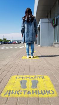 Ukraine, Kiev - April 23, 2020. Yellow pavement with warning. Keep your distance on the sidewalk. The text is in Ukrainian. Concept of maintaining social distance, quarantine or isolation