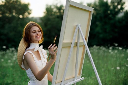 Woman in white dress paints a picture outdoors hobby creative. High quality photo