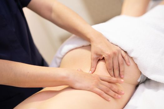 Young woman receiving a back massage in a spa center. Female patient is receiving treatment by professional therapist.