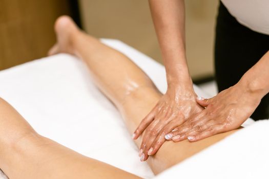 Woman receiving a leg massage with massage candle oil. Body care treatment in a beauty centre.