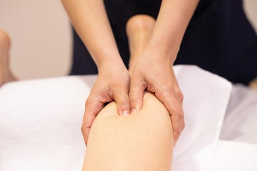 Medical massage at the leg in a physiotherapy center. Female physiotherapist inspecting her patient.