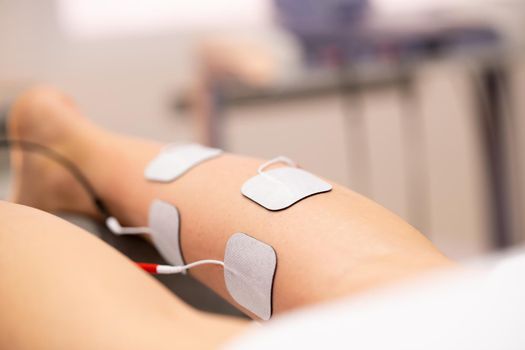 Electro stimulation in the leg in physical therapy to a young woman in a physiotherapy center.