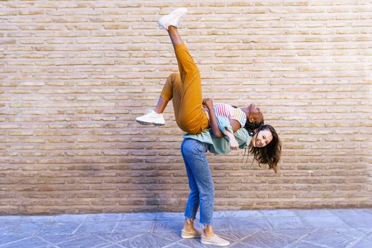 Funny multiethnic woman carrying her best friend piggyback outdoors