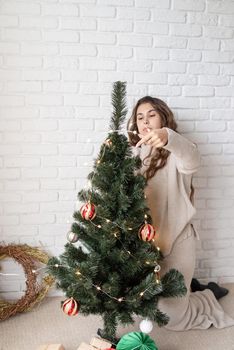 Merry christmas and happy new year. young attractive woman decorating the Christmas tree with fairy lights