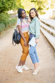 Two multiethnic female friends posing together with colorful casual clothing outdoors. Mutliethnic women.