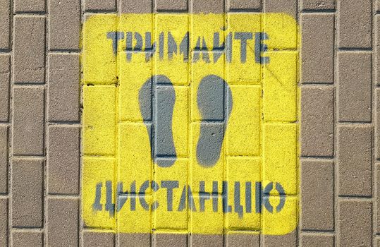 Ukraine, Kiev - April 23, 2020. Yellow sidewalk with the warning Keep your distance on the sidewalk. The text is in Ukrainian. Concept of maintaining social distance, quarantine or isolation.