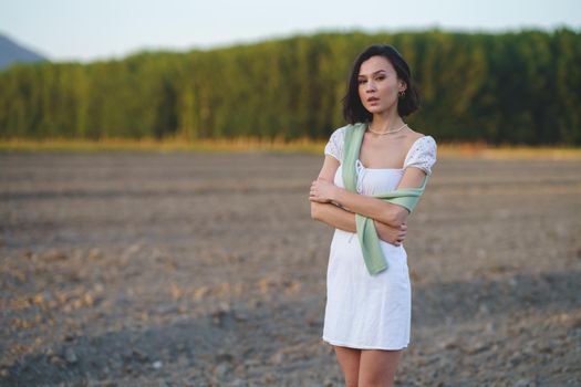 Pretty young Asian woman, walking in the countryside, wearing a white dress.