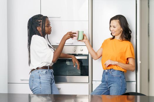 Two student friends taking a coffee break together at home Multiethnic women.