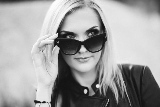 blonde girl in a black trouser suit with blue eyes on the background of a granite quarry from gray rubble