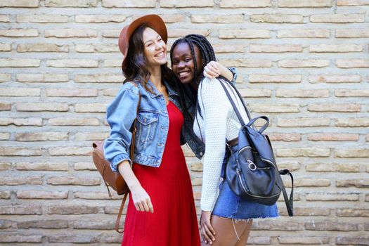 Two friends hugging in urban background. Multiethnic women.