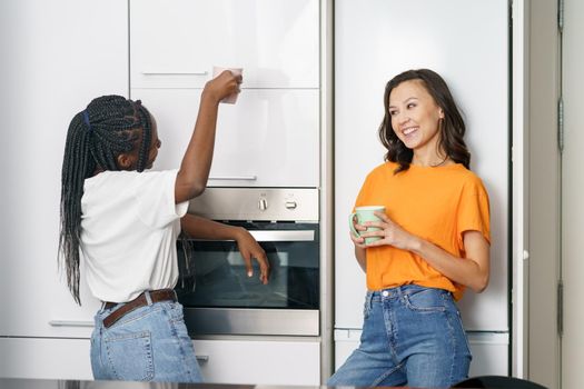 Two student friends taking a coffee break together at home Multiethnic women.