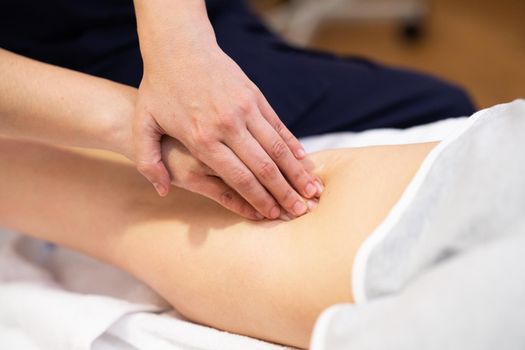 Medical massage at the leg in a physiotherapy center. Female physiotherapist inspecting her patient.