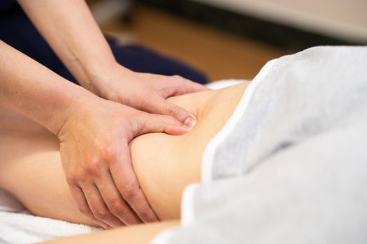 Medical massage at the leg in a physiotherapy center. Female physiotherapist inspecting her patient.