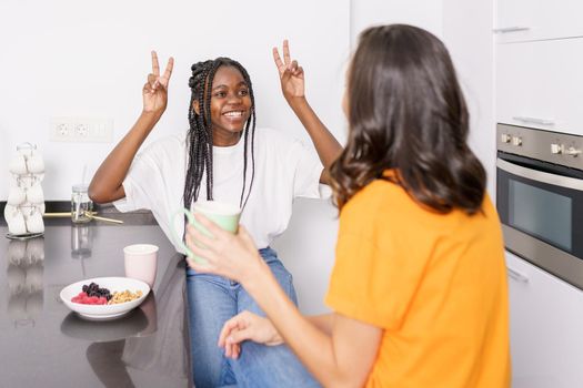 Two friends having a healthy snack while chatting at home. Multiethnic women.