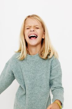 Portrait of a smiling little cutie in a sweater, grimaces posing studio. High quality photo