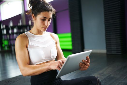 Athletic woman consulting her training on her smart phone at the gym