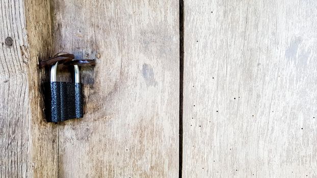 Old vintage metal padlock on a closed wooden door of an old farmhouse. The true style of the village. close-up. focus on the castle. Wooden background, texture. Copy space.
