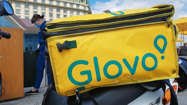 Ukraine, Kiev - August 29, 2020. Parked moped with yellow bag with Glovo logo near McDonald's close-up. Courier service that delivers goods ordered through a mobile application. Editorial photography