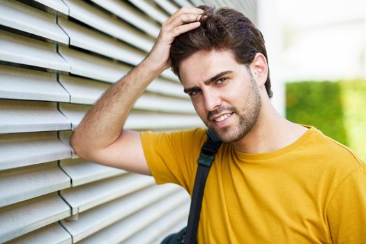 Portrait of young man with modern haircut in urban background