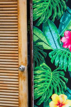 Little opened wooden rustic door and wall painted with flowers and leaves. Vertical photo, good for instagram stories as inspiration