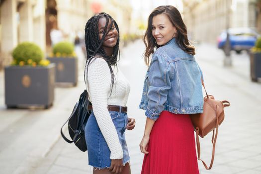 Two friends having fun together on the street. Multiethnic women.