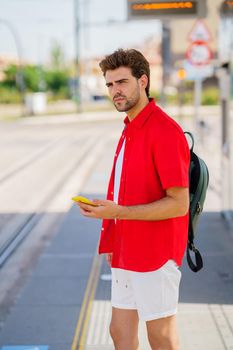 Student male waiting for a train at an outside station