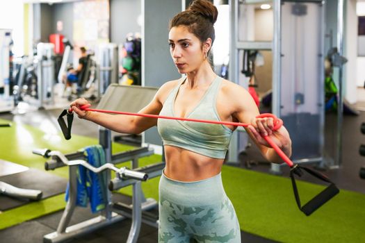 Young sportswoman warming up with fitness gums in the gym wearing sportswear