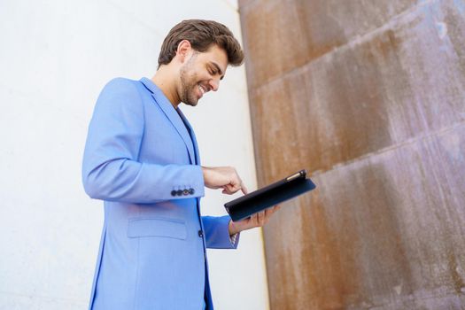 Young businessman using a digital tablet near an office building