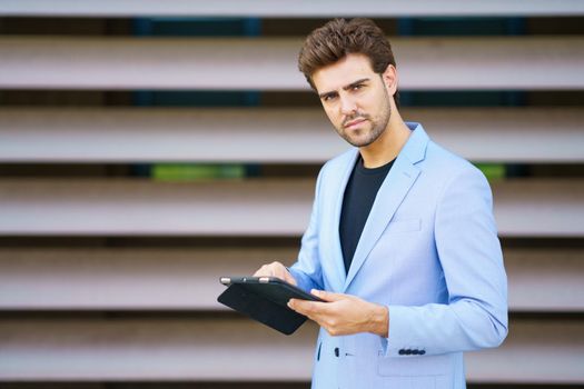 Man in a suit using a digital tablet outdoors