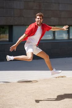 Young man wearing casual clothes jumping in urban background.