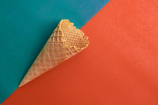 Top view at the empty waffle cone on orange and green background, special concept, enough place for text, diagonal position