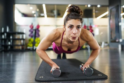 Woman doing push-ups with dumbbells in a fitness workout