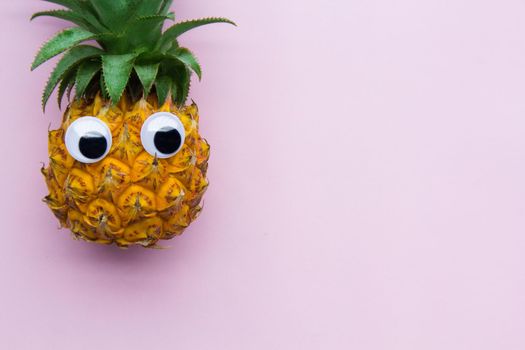 Fresh funny pineapple with googly eyes on pink background, enough place for text. .