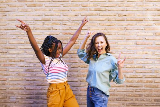 Two friends having fun together on the street. Multiethnic women.