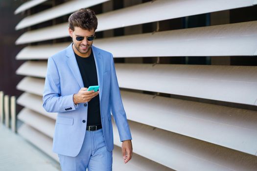 Young man walking down the street using his smartphone with a happy expression