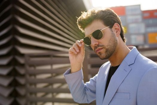 Young man, model of fashion, wearing sunglasses in urban background