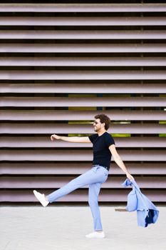 Happy young man walking funny in urban background