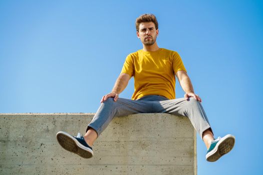 Young man sitting on a ledge looking around