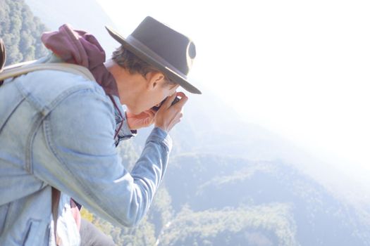 Explorer young man takes pictures with photo camera outdoor.