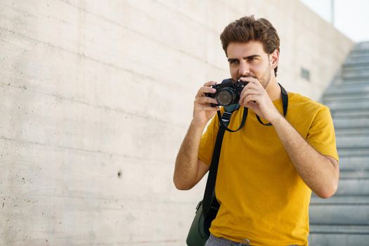 Millennial man taking photographs with a SLR camera outdoors