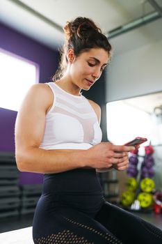 Athletic woman consulting her training on her smart phone at the gym