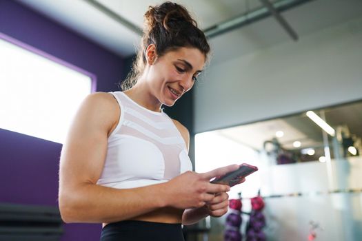 Athletic woman consulting her training on her smart phone at the gym