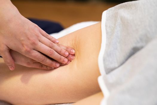 Medical massage at the leg in a physiotherapy center. Female physiotherapist inspecting her patient.