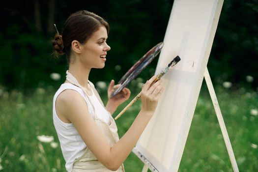 woman artist with palette of paints drawing easel nature hobby. High quality photo